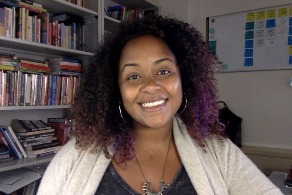 Woman with black and purple hair wearing a white sweater 