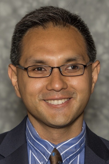 Portrait of someone in front of a gray background.